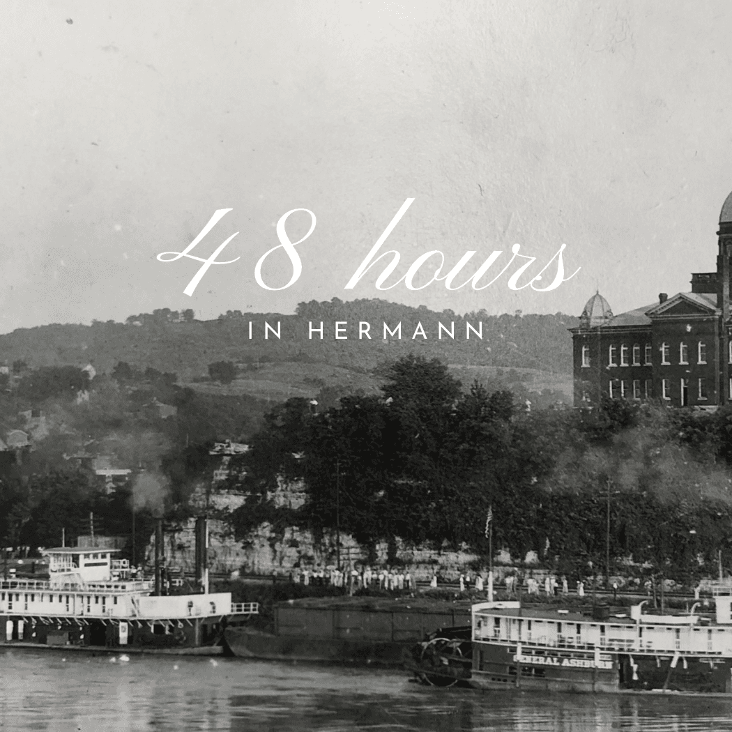 A historic black-and-white image of steamboats docked in Hermann, with the text "48 hours in Hermann" overlaying the scene. A historic black-and-white image of steamboats docked in Hermann, with the text "48 hours in Hermann" overlaying the scene.
