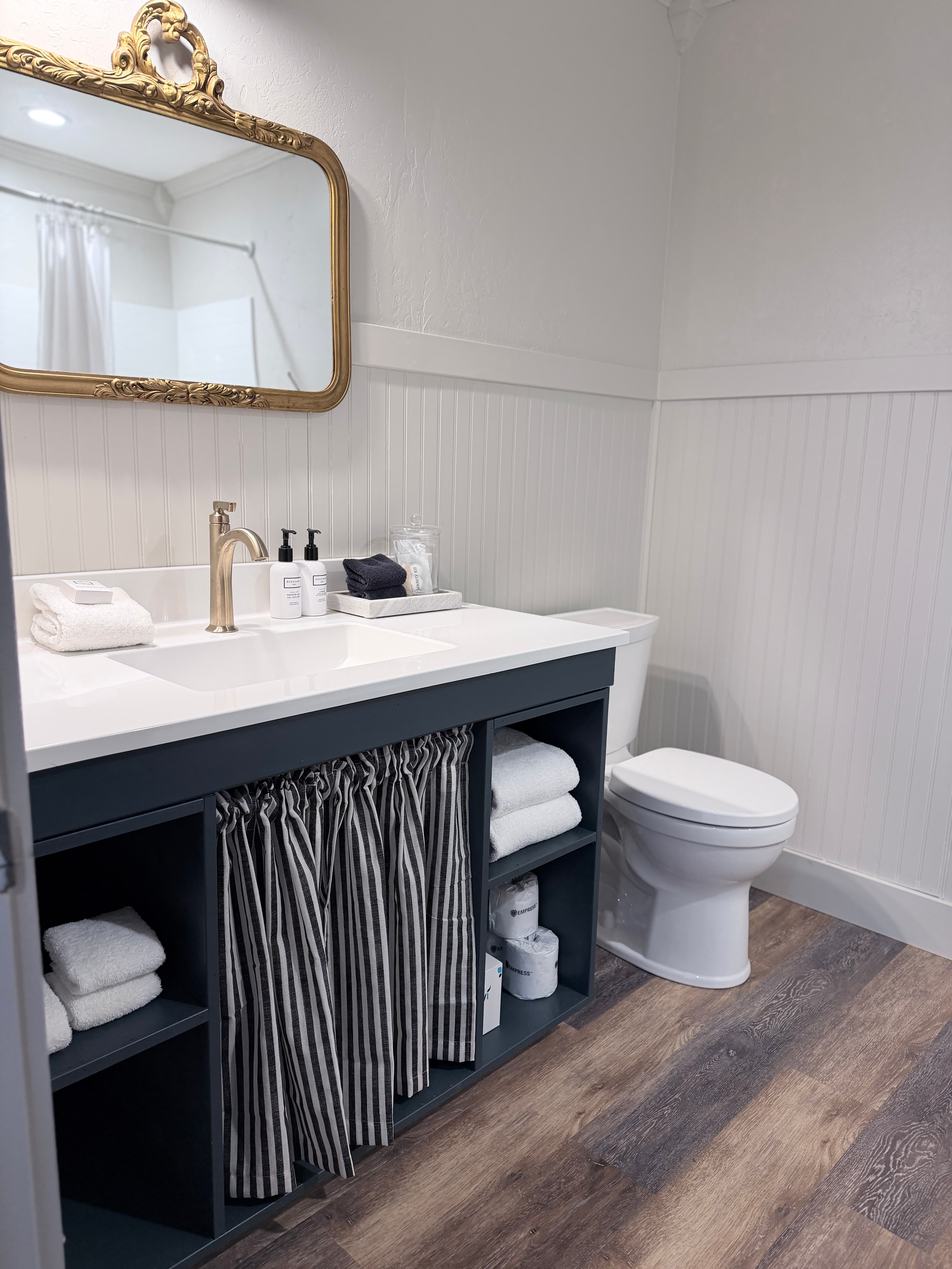 A modern bathroom featuring a dark vanity, a large mirror, and neatly arranged towels.