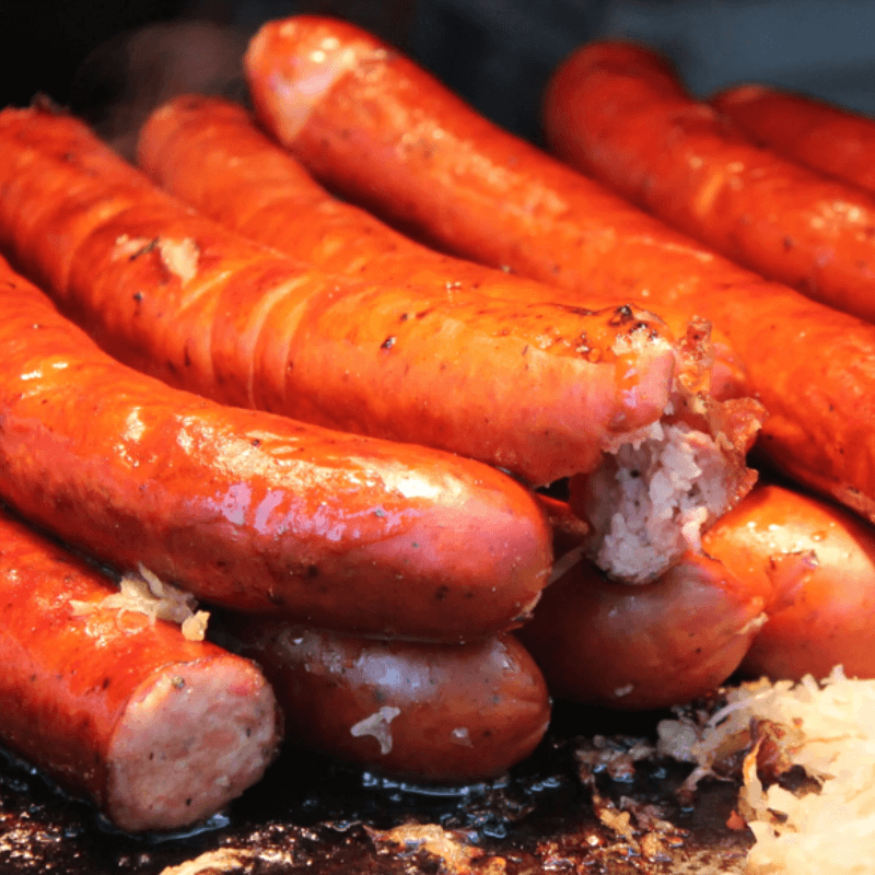 A close-up of several juicy, grilled sausages on a hot grill.