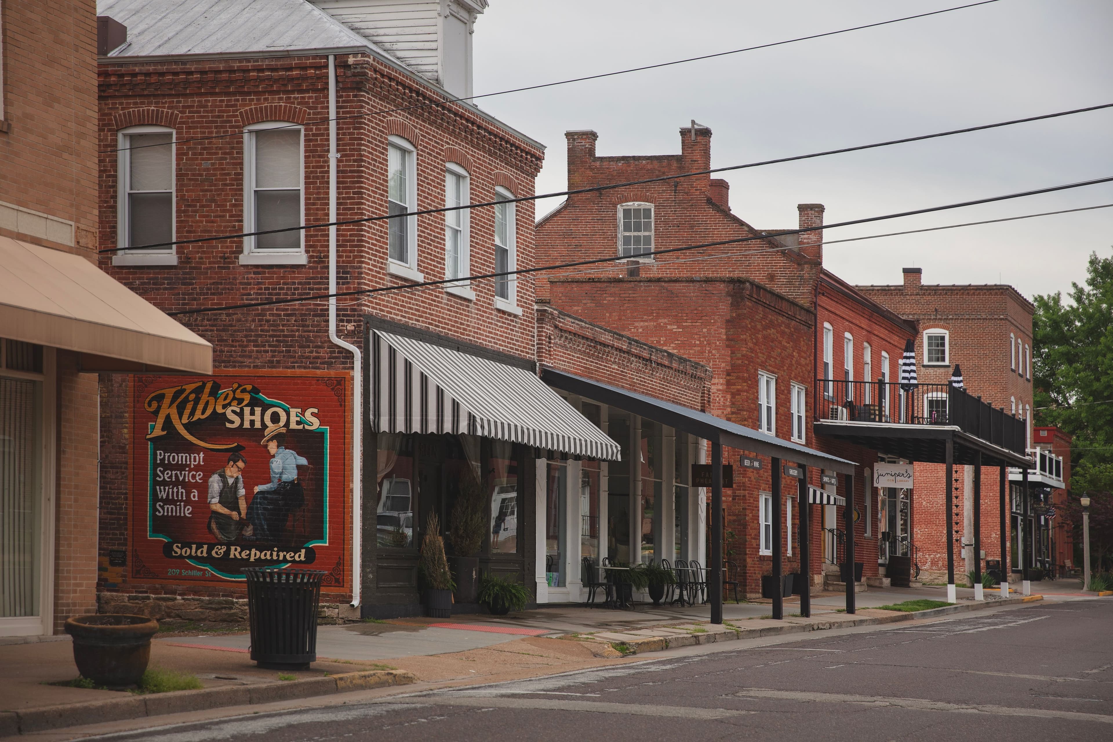 A quaint street scene featuring brick buildings and a sign for Kibe's Shoes.