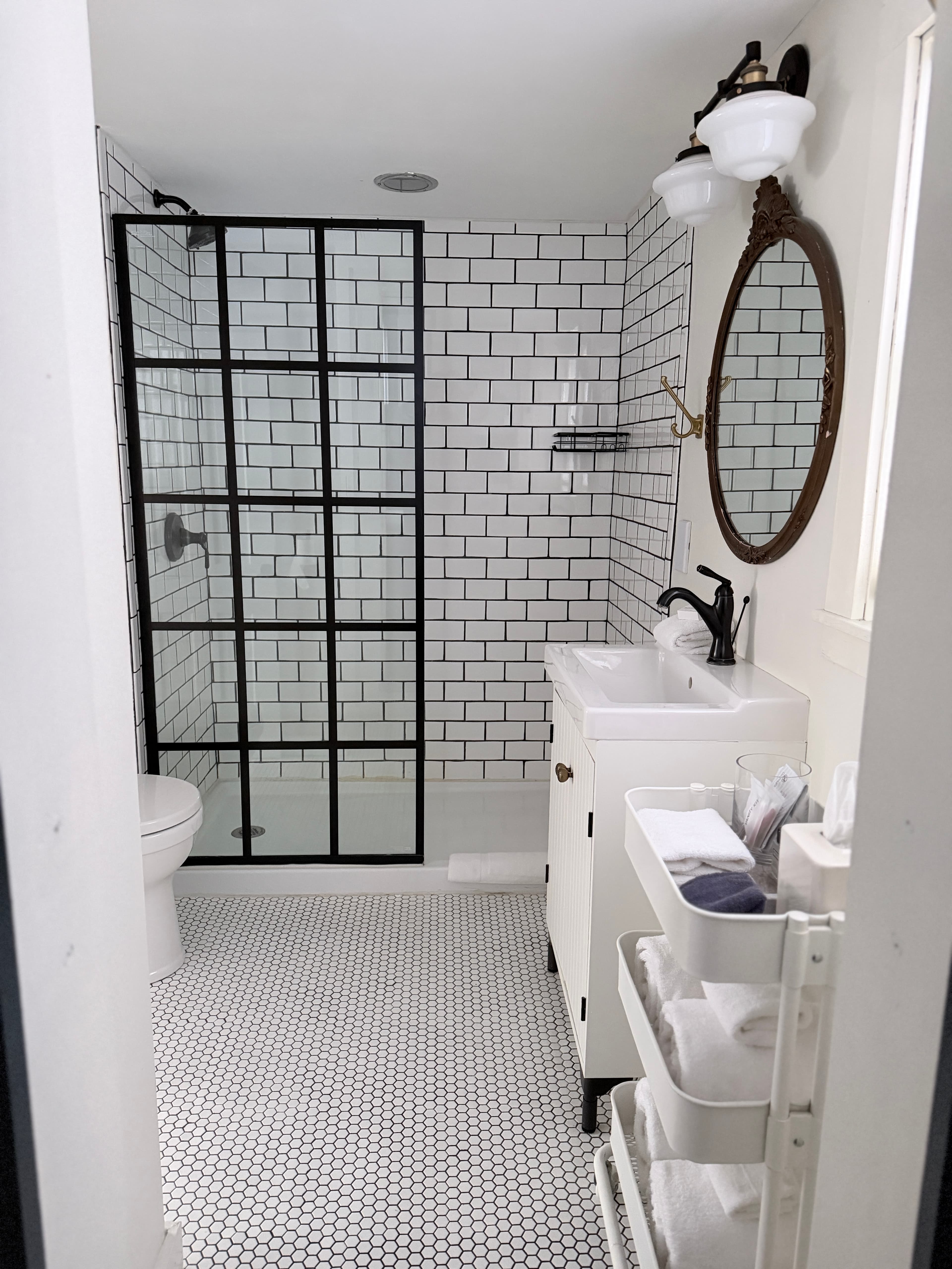 Bathroom featuring a glass shower, white vanity, and black and white tile accents.
