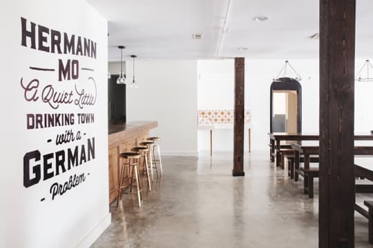 Interior of a bar featuring a wall mural that reads "Hermann Mo A quiet little drinking town with a German Problem."